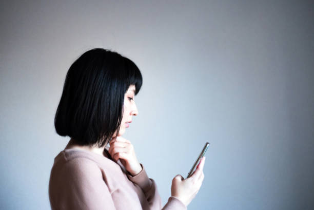 istock Asian woman looking at her smartphone with a serious expression. 1295319271