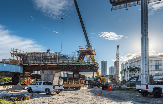 Miami, FL, USA - January 7, 2021: Heavy machinery and workers working on the construction of a new viaduct along the north of downtown Miami, where new luxury housing complexes are being developed.