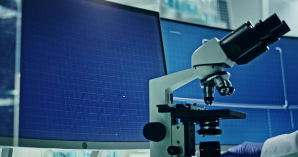 istock Laboratory equipment, microscope and computers. Research on screens. Side view of scientist 1295324636