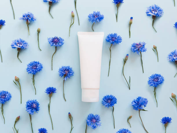 istock Cosmetic bottle container and blue cornflowers on pastel blue background. 1295325585
