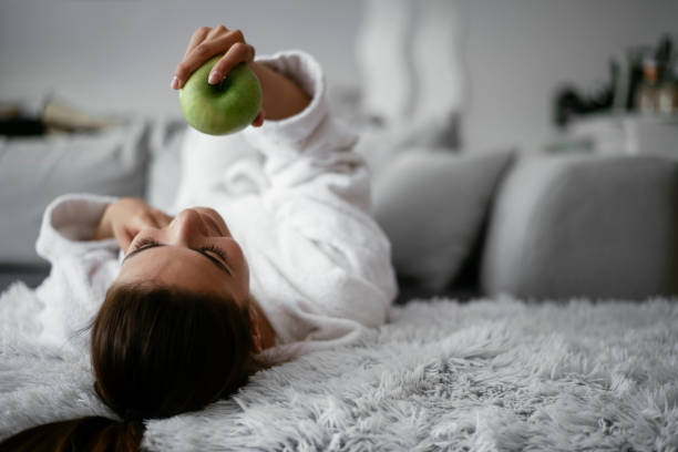 istock Beautiful woman in bathrobe eating apple. 1295326103