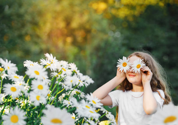 istock Child with daisy eyes on green background in a summer park. 1295326436