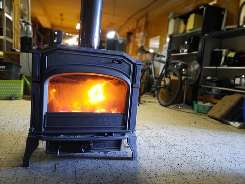 Woodstove cast iron with orange flames in winter in a shed with tiled floor