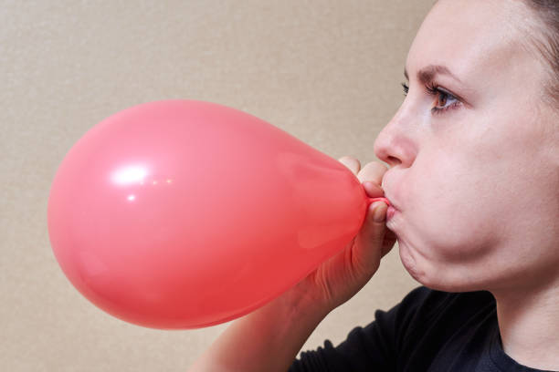 若い女性は風船、休日やパーティーのテーマを膨らまします。 - inflating balloon women growth ストックフォトと画像