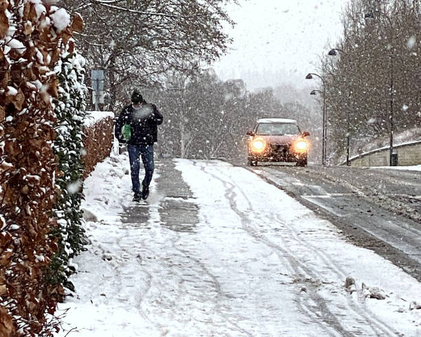 uomo che cammina sul marciapiede sgomberato nella bufera di neve - denmark street street light design foto e immagini stock