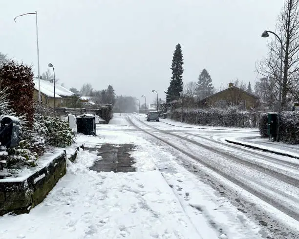 Empty street covered with snow, except for one cleared pavement.