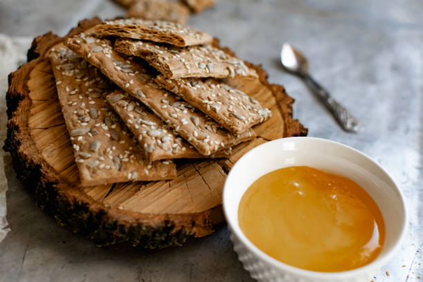 istock Healthy and nutritious diet bread with sesame and sunflower seeds on a thin crunchy malt base. Near natural bee honey and a wooden 1295330156
