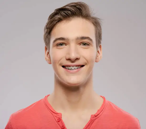 Smiling teen boy with braces on his teeth. Close-up portrait of a beautiful young boy with even healthy teeth.