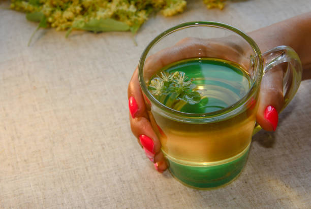 istock Lime tea in women's hands on the background of a linen tablecloth. 1295336877