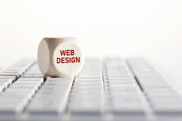 The word web design with arrow icon on wooden cube with computer keyboard. Business, technology and internet concept.