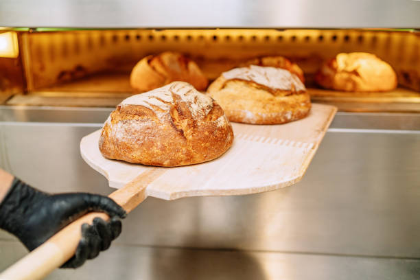 baker poner pan en el horno de panadería acobardando en el suelo de la panadería - pan fotografías e imágenes de stock