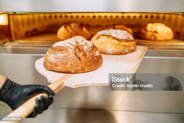 Baker Putting Bread In The Bakery Oven Cowering On The Floor Of The Bakery Stock Photo - Download Image Now