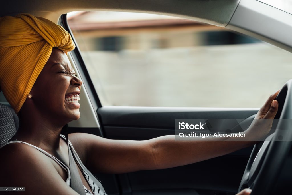 Driving and smiling Young African woman driving a car Car Stock Photo