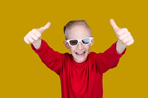 istock a child in a red jacket with glasses on a yellow background 1295341114