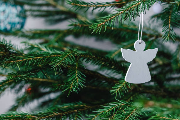 de witte houten engel die van het kerstboom stuk speelgoed op een sparrentak hangt - piek kerstversiering stockfoto's en -beelden