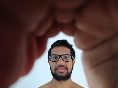 View of Asian young man through hand with wearing specs - stock photo