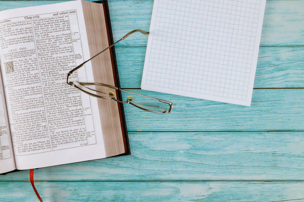 istock Open Holy Bible lying on wooden table in a reading on notepad 1295348307