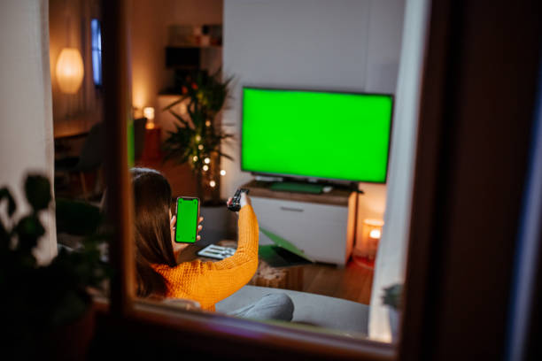 istock Woman sitting on couch watching tv 1295348812