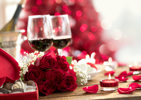 Valentine's Day dining table for two with red wine, roses & chocolates