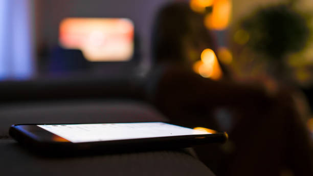 istock Upset woman sitting on floor with mobile phone on sofa during night 1295351084