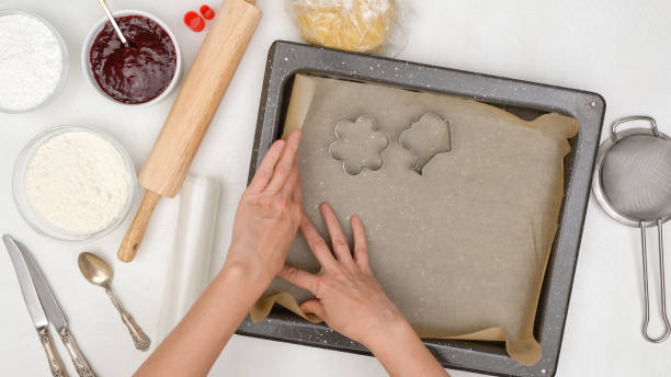 istock Woman hands line baking pan with parchment paper. Shortbread cookie recipe. Step by step baking process 1295354582