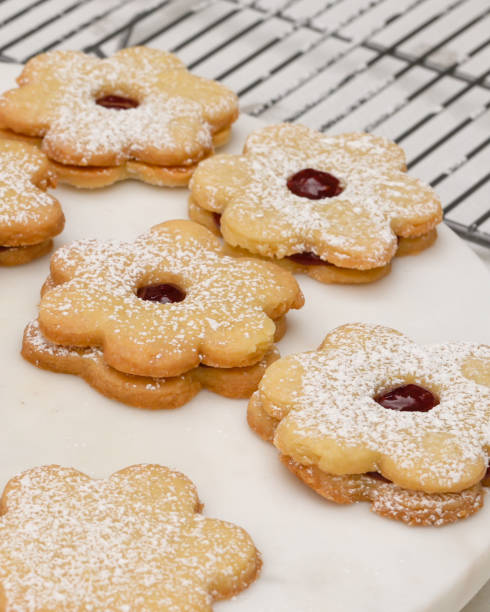 istock Flower shaped shortbread cookies filled with raspberry jam close up on cooling rack, vertical banner 1295354807