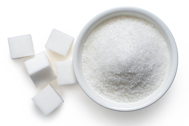 White sugar cubes and granulated sugar. Refined granulated sugar in white ceramic bowl next to white sugar cubes isolated on white. Top view. sugar cube stock pictures, royalty-free photos & images