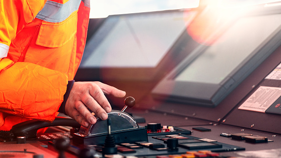 Captain crew officer hand on ship's control bridge dashboard with navigation equipment on the vessel bridge.