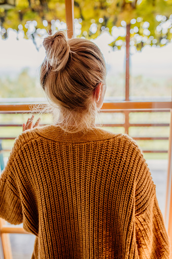 Woman standing besides window at home