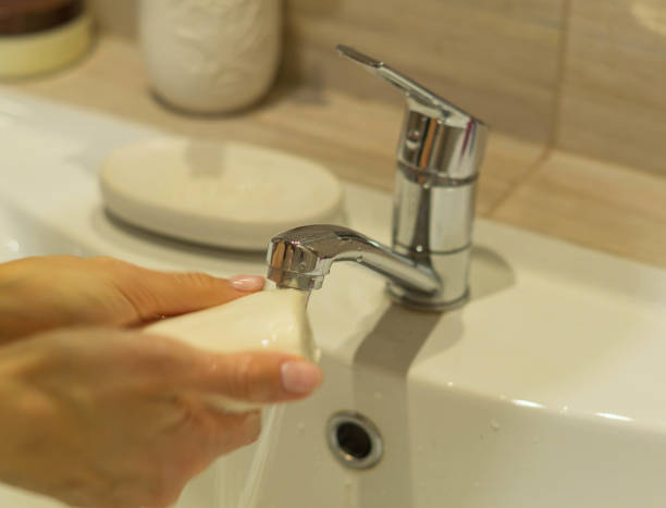 istock Black person washing hands with soap under running water 1295358152