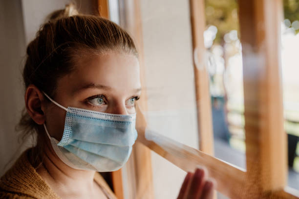 istock Woman wearing protective mask and looking through window 1295358204