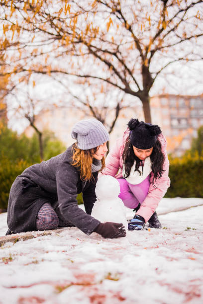 bambini in famiglia e giovane donna giocano con la neve in un parco di madrid - 12 18 months foto e immagini stock