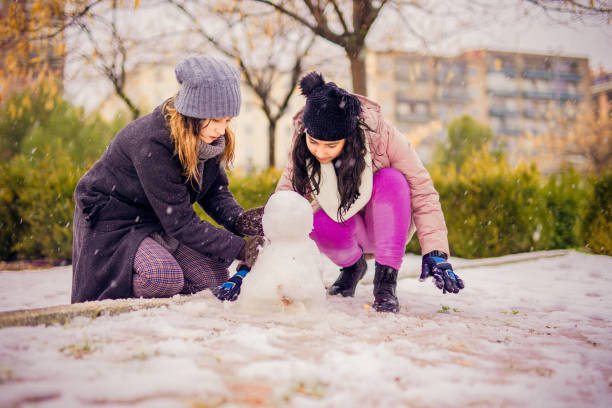 junge familienkinder und junge frau spielen mit schnee in einem park in madrid - 12 18 months stock-fotos und bilder