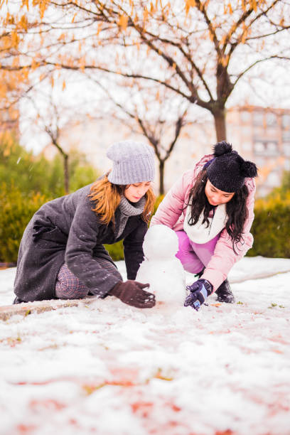 junge familienkinder und junge frau spielen mit schnee in einem park in madrid - 12 18 months stock-fotos und bilder