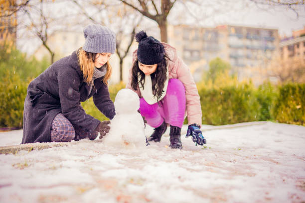junge familienkinder und junge frau spielen mit schnee in einem park in madrid - 12 18 months stock-fotos und bilder