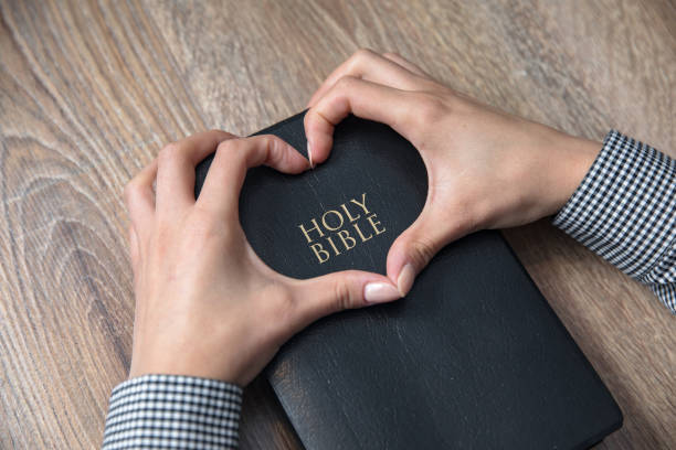 istock woman hand heart on Holy Bible 1295367709