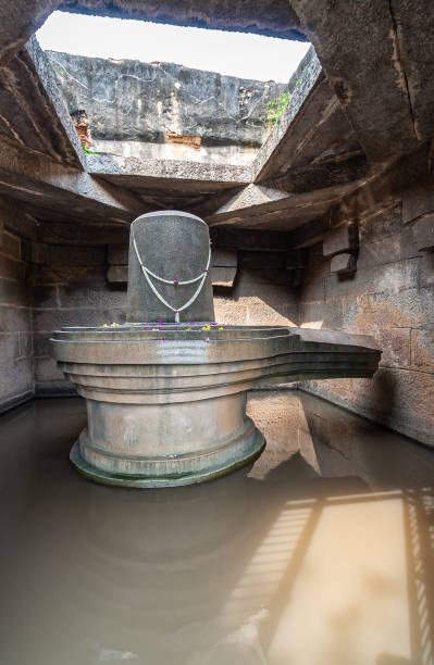 Portrait, Shivalingam statue at Badavilinga Temple, Hampi, Karnataka, India. Hampi, Karnataka, India - November 5, 2013: Badavilinga Temple. Portrait of massive gray stone monolith statue of Shivalingam symbol standing in water in small chamber with open ceiling. lingam yoni stock pictures, royalty-free photos & images