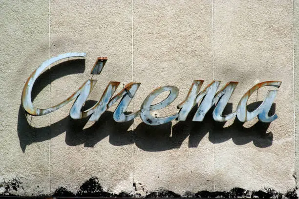 damaged and rusty vintage cinema sign hanging on a wall