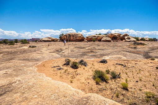 Canyonlands NP, Utah, USA - July 20, 2020: Lone female tourist is hiking in Canyonlands National Park in Utah, USA.