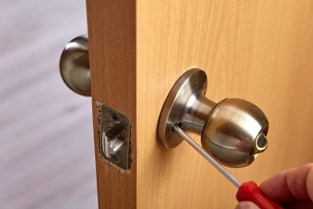 istock Locksmith unscrews door handle to repair lock. 1295374526