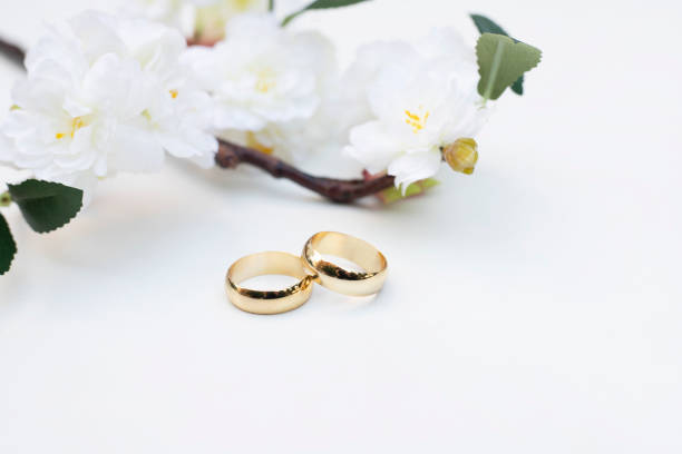 istock Flowers and two golden wedding rings on white background. 1295378468