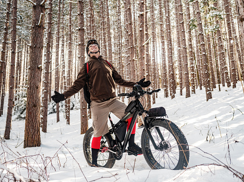 Adult man riding fat bicycle in winter. Outdoor conservation area of Southern Ontario, Canada in January,
