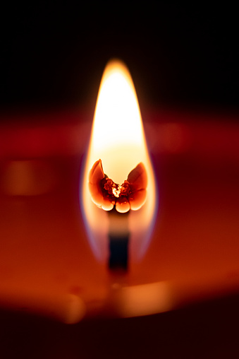 Extreme close up shot of a flame and red candle