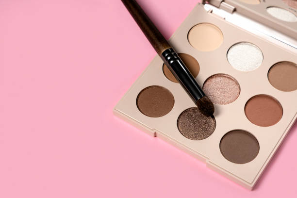 istock Daily eyeshadow palette in brown tones on a pink background top view with copy space. makeup brush, decorative cosmetics for the face. Flat lay female accessories. Nobody 1295383670