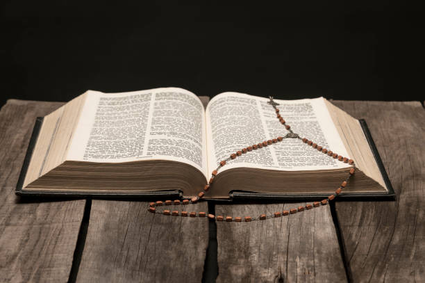 istock Holy bible open on rustic wooden table in dark night. 1295387140