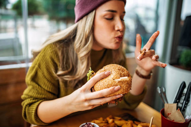 Tastes like heaven Young woman eating burger burgers stock pictures, royalty-free photos & images