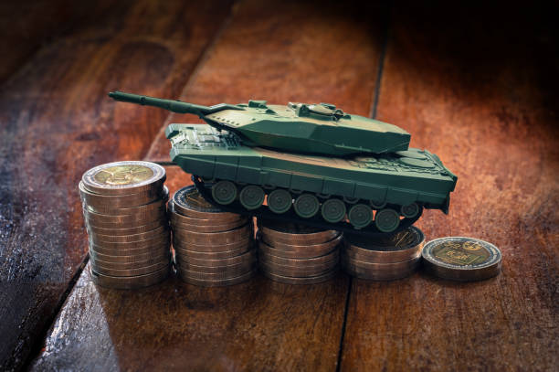 istock Small plastic tank on money coins. 1295388110