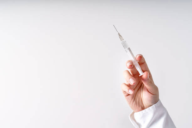 Close up on hand of unknown caucasian woman doctor holding syringe with needle and vaccine injection in front of white wall - covid-19 vaccination concept healthcare and medicine copy space Close up on hand of unknown caucasian woman doctor holding syringe with needle and vaccine injection in front of white wall - covid-19 vaccination concept healthcare and medicine copy space human papilloma virus photos stock pictures, royalty-free photos & images