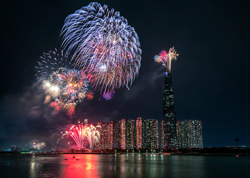 Fireworks happy new year 2021 light up sky over business district in Ho Chi Minh city view from Landmark 81 riverside. Landmark 81 is the tallest building in Vietnam