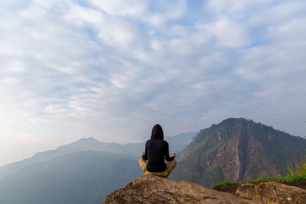 istock Relaxed woman practicing sunrise yoga sitting on a rock 1295411899